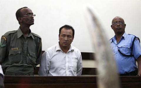 Tang Yong Jian (C), a Chinese national, stands guarded inside the dock at the Makadara Law courts in Kenya's capital Nairobi