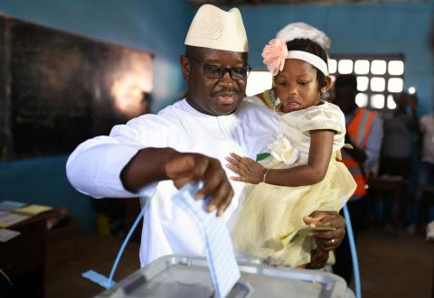 Julius Maada Bio, the presidential candidate for the Sierra Leone People's Party (SLPP), carries his daughter as he casts his vote during Sierra Leone's general election in Freetown, Sierra Leone, March 7, 2018. PHOTO BY REUTERS/Olivia Acland
