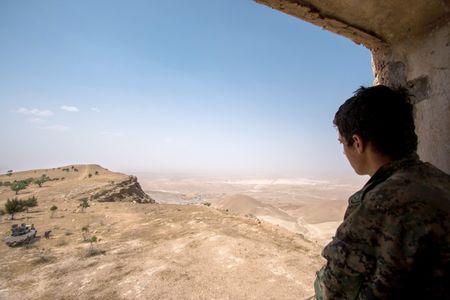 A Kurdish People's Protection Units (YPG) fighter stands on a lookout point on Abd al-Aziz mountain, Hasaka province, May 20, 2015. PHOTO BY REUTERS/Rodi Said