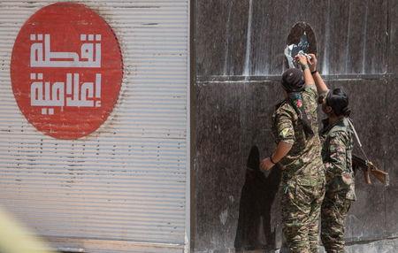Kurdish People's Protection Units (YPG) fighters remove an Islamic State sticker in Tel Abyad town, Raqqa governorate, June 16, 2015. PHOTO BY REUTERS/Rodi Said