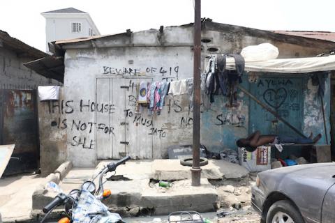 A man takes a daytime nap on a bench in front of a dilapidated building with a warning notice reading "This house is not for sale" written on the wall of the house in Lagos, Nigeria, April 1, 2019. PHOTO BY REUTERS/Temilade Adelaja