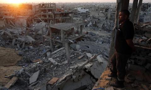 A Palestinian man looks out of his heavily damaged house at neighbouring houses which witnesses said were destroyed during the Israeli offensive, in the east of Gaza City, September 3, 2014. PHOTO BY REUTERS/Suhaib Salem