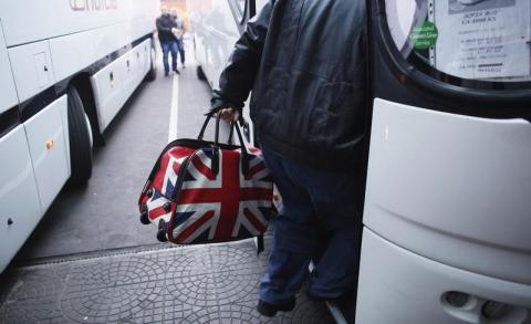 A man carrying a bag adorned with a British Union Jack flag steps into a bus departing from Sofia's central bus station to London via Austria, Germany and France, January 2, 2014. PHOTO BY REUTERS/Stoyan Nenov