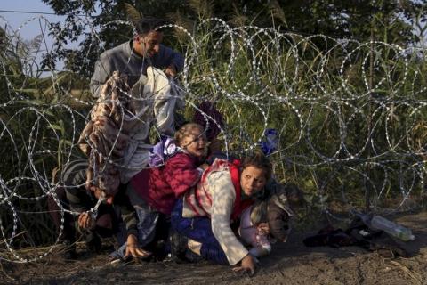 Syrian migrants cross under a fence as they enter Hungary at the border with Serbia, near Roszke, August 27, 2015. PHOTO BY REUTERS/Bernadett Szabo