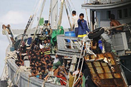 A Myanmar military officer gestures from a boat packed with migrants off Leik Island in the Andaman Sea, May 31, 2015. PHOTO BY REUTERS/Soe Zeya Tun