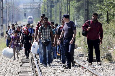 A Greek police officer guides migrants arriving to enter Macedonia, near the border with Greece, August 27, 2015. Migrants are trekking from the southern Macedonian border near Gevhelija to the northern border with Serbia on their way to Western Europe. PHOTO BY REUTERS/Ognen Teofilovski