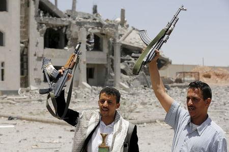 Houthi militants gesture in the yard of the residence of the military commander of the Houthi militant group, Abdullah Yahya al Hakim, after it was hit by an airstrike, in Sanaa, April 28, 2015. PHOTO BY REUTERS/Khaled Abdullah