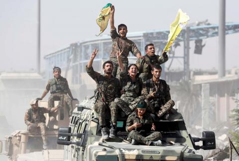 Kurdish-led militiamen ride atop military vehicles as they celebrate victory over Islamic State in Raqqa, Syria, October 17, 2017. PHOTO BY REUTERS/Erik De Castro