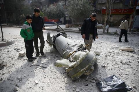 People inspect missile remains in the besieged town of Douma, in eastern Ghouta, in Damascus, Syria, February 23, 2018. PHOTO BY REUTERS/Bassam Khabieh