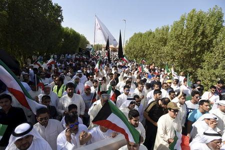 Mourners hold flags as the bodies of victims of Friday's bombing are buried in Al Jafariya cemetery in Suleibikhat, Kuwait, June 27, 2015. PHOTO BY REUTERS/Jassim Mohammed