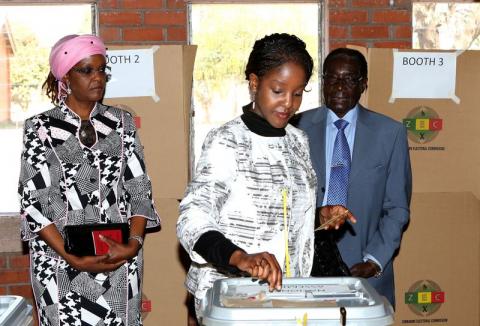 Zimbabwe's President Robert Mugabe (R) and his wife Grace (L) look on as their daughter Bona casts her vote in Highfields outside Harare, 2013. PHOTO BY REUTERS/Siphiwe Sibeko