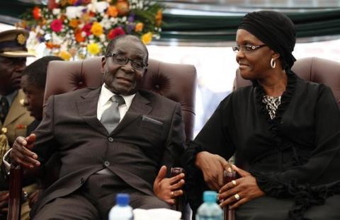 Zimbabwe President Robert Mugabe (L) speaks to his wife Grace during the funeral of his sister, Bridget, in the village of Zvimba, 90 km (55 miles) west of Harare