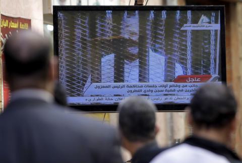 Egyptians watch television showing the trial of ousted Egyptian president Mohamed Mursi, in Cairo