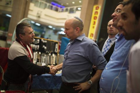 Israel's Economy Minister Naftali Bennett (R), head of far-right Jewish Home party, shakes hands with a Russian speaking immigrant as he campaigns in the southern city of Ashkelon, February 3, 2015. PHOTO BY REUTERS/Amir Cohen