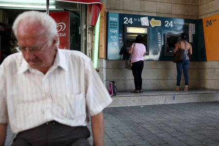 People withdraw money from automated teller machines in Nicosia, Cyprus, June 21, 2015. PHOTO BY REUTERS/Yiannis Kourtoglou