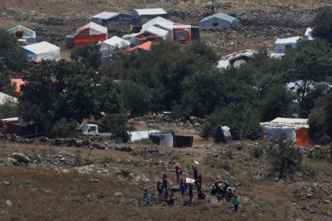People wave white cloths next to the refugee tents erected near the border fence between Israel and Syria from its Syrian side as it is seen from the Israeli-occupied Golan Heights near the Israeli Syrian border, July 17, 2018. PHOTO BY REUTERS/Ronen Zvulun