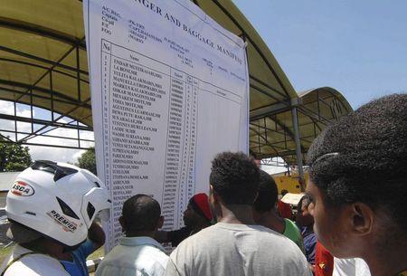 People look at a passenger and baggage manifest of the crashed Trigana Air Service flight at the airport in Sentani, near Jayapura, Papua province, Indonesia, August 17, 2015, in this photo taken by Antara Foto. REUTERS/Lucky R/Antara Foto
