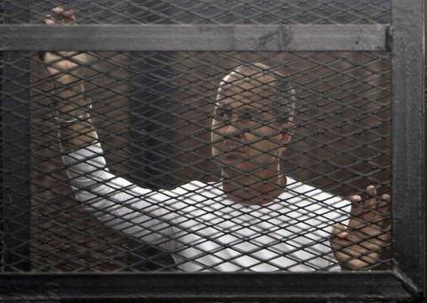 Al Jazeera journalist Peter Greste of Australia stands in a metal cage during his trial in a court in Cairo, March 24, 2014. PHOTO BY REUTERS/Al Youm Al Saabi Newspaper