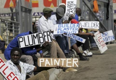 Men hold placards offering temporal employment services in Glenvista, south of Johannesburg, file. PHOTO BY REUTERS/Siphiwe Sibeko
