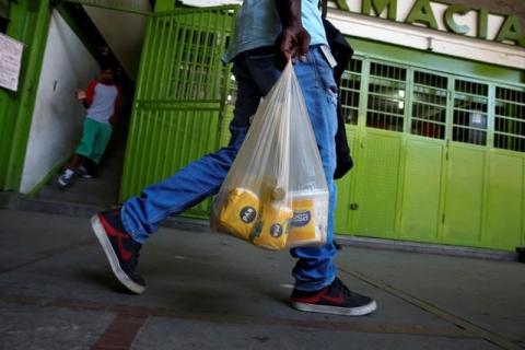 Man carries a plastic bag of basic foods. PHOTO BY REUTERS/Carlos Garcia Rawlins