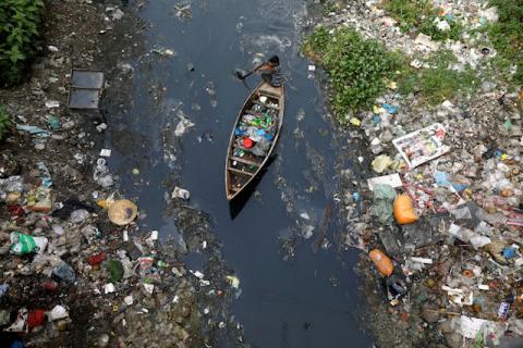 A man on a boat collects plastic materials from dirty water in Dhaka, Bangladesh, April 17, 2019. PHOTO BY REUTERS/Mohammad Ponir Hossain