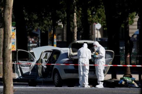 Members of the scientific police inspect a burned car at the scene of an incident in which a car rammed a gendarmerie van on the Champs-Elysees Avenue in Paris, France, June 19, 2017. PHOTO BY REUTERS/Gonzalo Fuentes