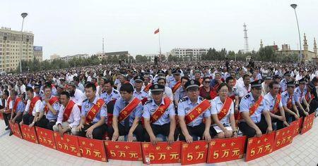 Police wearing sashes hold placards during a ceremony to award those who the authorities say participated in "the crackdown of violence and terrorists activities" in Hotan, Xinjiang Uighur Autonomous Region, August 3, 2014. PHOTO BY REUTERS/Stringer