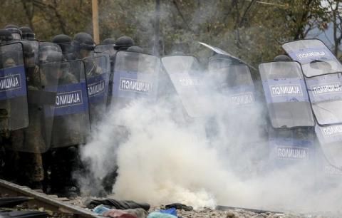 Macedonian police officers try to take cover from tear gas thrown back by a stranded migrant, as minor clashes broke out during a protest against the building of a metal fence at the Greek-Macedonian borders near the village of Idomeni, Greece, November 28, 2015. PHOTO BY REUTERS/Yannis Behrakis