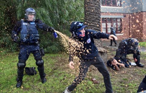A policeman deploys capsicum spray towards a protester during clashes in the Melbourne suburb of Coburg, Australia, May 28, 2016. PHOTO BY REUTERS/Julian Smith