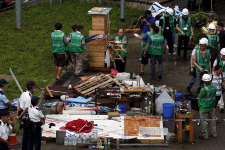 Policemen look on as workers from the Lands Department remove encampments outside government headquarters in Hong Kong, China, June 24, 2015. PHOTO BY REUTERS/Bobby Yip