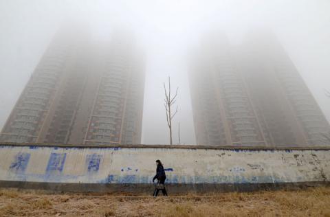A woman wearing a mask walks past buildings on a polluted day in Handan, Hebei province, China, January 12, 2019. PHOTO BY REUTERS/Stringer