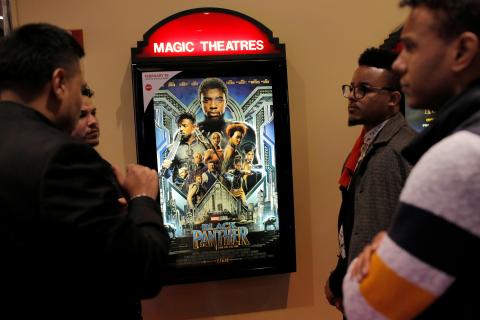 A group of men gather in front of a poster advertising the film "Black Panther" on its opening night of screenings at the AMC Magic Johnson Harlem 9 cinemas in Manhattan. PHOTO BY REUTERS/Andrew Kelly