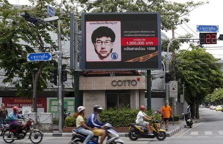 People ride their motorcycles past a digital billboard showing a sketch of the main suspect in Monday's attack on Erawan shrine, in Bangkok, Thailand, August 23, 2015. PHOTO BY REUTERS/Chaiwat Subprasom