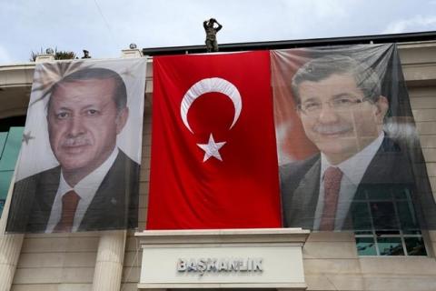 A special forces police officer takes security measures as he stands on top of a building where the portraits of Turkey's President Tayyip Erdogan (L), Prime Minister Ahmet Davutoglu and a Turkish flag are displayed in Istanbul, Turkey, June 3, 2015. PHOTO BY REUTERS/Murad Sezer