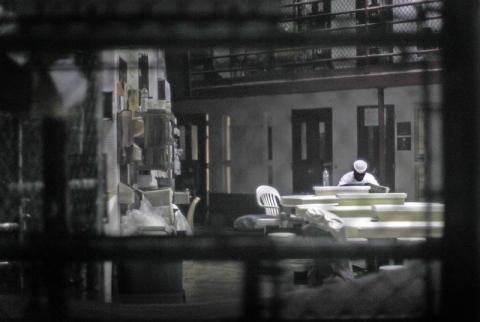 An unidentified prisoner reads a newspaper in a communal cellblock at Camp VI, a prison used to house detainees at Guantanamo Bay U.S. Naval Base