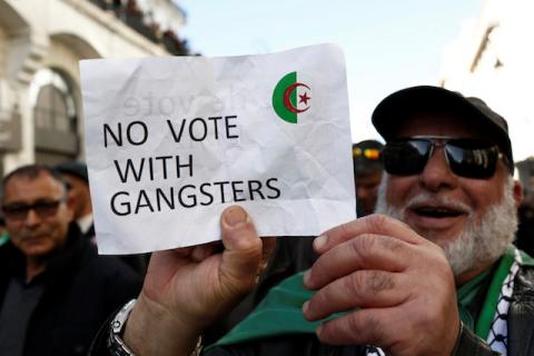 A demonstrator holds a sign as people take part in a protest to demand for the presidential election scheduled for next week to be cancelled, in Algiers, Algeria. PHOTO BY REUTERS/Ramzi Boudina
