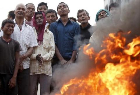 Protesters stand near a burning tyre as they gather to block the highway connecting Nepal to India during a general strike called by Madhesi protesters demonstrating against the new constitution in Birgunj, Nepal, November 5, 2015. PHOTO BY REUTERS/Navesh Chitrakar
