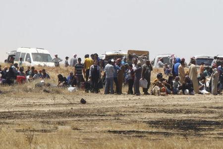 Syrian refugees wait near the border fences as they are pictured from the Turkish side of the border, near Akcakale in Sanliurfa province, Turkey, June 11, 2015. PHOTO BY REUTERS/Osman Orsal