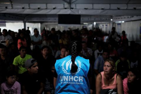 A member of United Nations High Commissioner for Refugees (UNHCR) talks with Venezuelans as they queue in line to receive a vaccine after showing their passports or identity cards at the Pacaraima border control, Roraima state, Brazil, August 8, 2018. PHOTO BY REUTERS/Nacho Doce