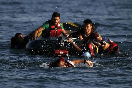 A Syrian refugee swims towards a beach as others are seen on a dinghy whose engine broke down a few hundred meters from the shore of the Greek island of Kos after crossing over from Turkey, August 17, 2015.  PHOTO BY REUTERS/Alkis Konstantinidis