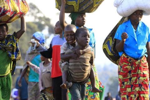 A boy, displaced by fighting between the Congolese army and M23 rebels in Bunagana in the eastern Democratic Republic of Congo, carries a crying child on his back as they make their way home after spending a night in the Ugandan town of Bunagana, 491 km (305 miles) west of capital Kampala
