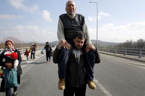 Stranded refugees walk through a motorway towards the Greek-Macedonian border near the Greek village of Idomeni as at least 20,000 refugees and migrants have been stranded in Greece after border shutdowns through the Balkans route to central and northern Europe, February 26, 2016. PHOTO BY REUTERS/Yannis Behrakis