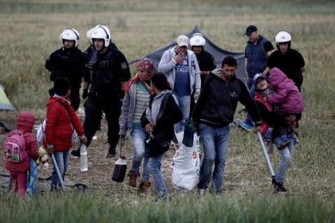 A refugee family carry their belongings during a police operation at a refugee camp at the border between Greece and Macedonia, near the village of Idomeni, Greece, 24 May 2016. PHOTO BY REUTERS/Yannis Kolesidis