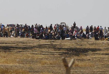 Syrian refugees wait near the border fences as they are pictured from the Turkish side of the border, near Akcakale in Sanliurfa province, Turkey, June 11, 2015. PHOTO BY REUTERS/Osman Orsal