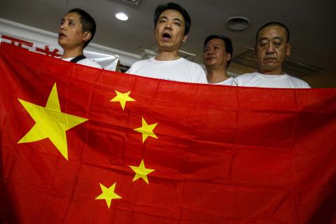 Chinese relatives of passengers onboard the missing Malaysia Airlines flight MH370 hold China's national flag during a news conference at The Holiday Villa in Subang Jaya
