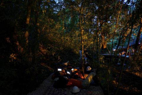Rescue workers use mobile phones as they take a short break near the Tham Luang cave, where 12 boys and their soccer coach are trapped, in the northern province of Chiang Rai, Thailand, July 6, 2018. PHOTO BY REUTERS/Athit Perawongmetha