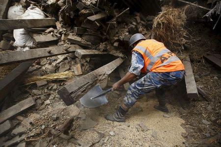 Rescue team member works to dig out the trapped body of a woman from a collapsed house a day after an earthquake in Bhaktapur, Nepal April 26, 2015. PHOTO BY REUTERS/Navesh Chitrakar