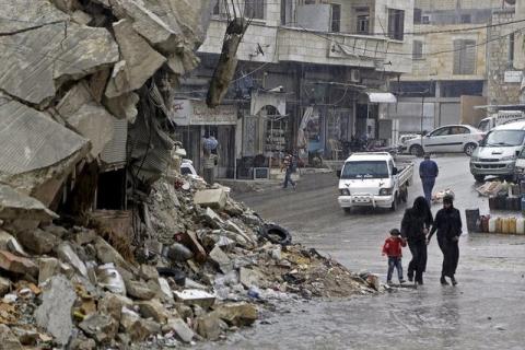 Civilians walk in the rain past a damaged building in the rebel-controlled area of Maaret al-Numan town in Idlib province, Syria, October 28, 2015. PHOTO BY REUTERS/Khalil Ashawi