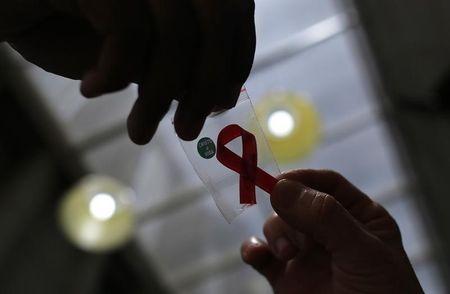 A nurse (L) hands out a red ribbon to a woman, to mark World Aids Day, at the entrance of Emilio Ribas Hospital, in Sao Paulo, December 1, 2014. PHOTO BY REUTERS/Nacho Doce