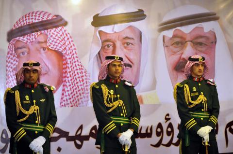 Saudi royal guards stand on duty in front of portraits of King Abdullah bin Abdulaziz (R), Crown Prince Salman bin Abdulaziz (C) and second deputy Prime Minister Muqrin bin Abdulaziz during the traditional Saudi dance known as "Arda" at the Janadriya culture festival at Der'iya in Riyadh